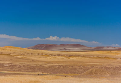 Scenic view of desert against blue sky