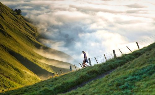 Full length of man climbing on grass against sky