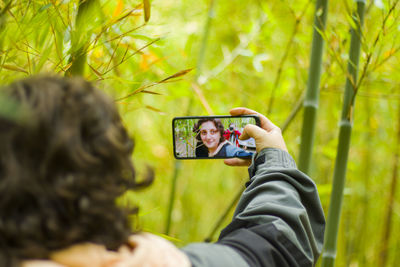 Woman takes self photo, mobile phone and nature background