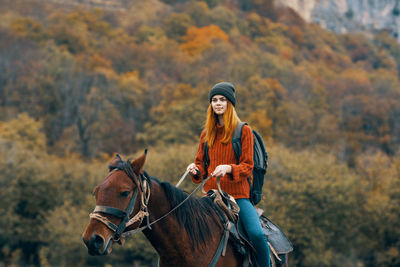 Young woman riding motorcycle on autumn leaves