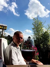 Mature man looking at wineglass on table during sunny day