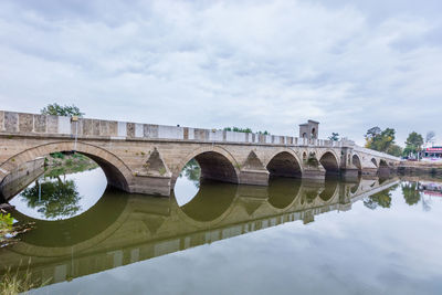 Arch bridge over river against sky