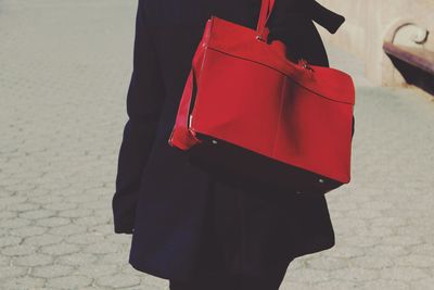 Midsection of woman with red shoulder bag standing on street