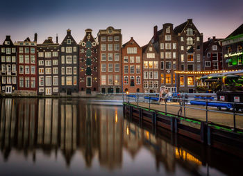 Canal by buildings at dusk