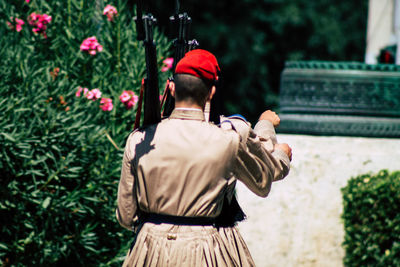 Rear view of man standing by statue against plants