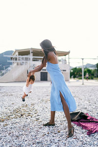 Rear view of women on beach against clear sky