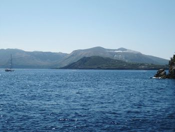 Scenic view of sea and mountains against clear blue sky