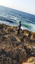 Full length of man standing on beach against clear sky