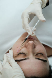 Cosmetologist applying eye mesotherapy to female patient