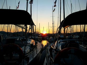 Sailboats moored at harbor during sunset