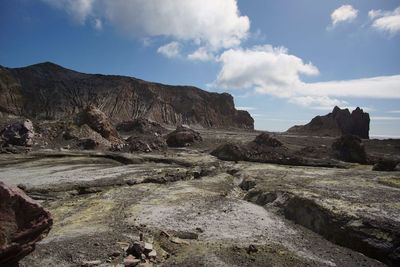 Rock formations on landscape against cloudy sky