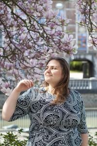 Portrait of a beautiful plump caucasian confident woman in magnolia flowers