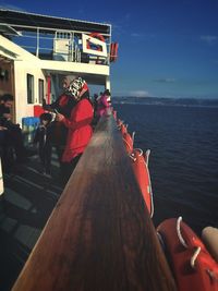 People on boat in sea against sky