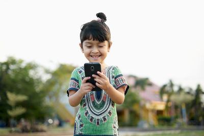 Girl using phone against sky