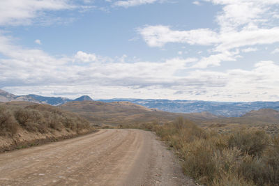 Road leading towards mountains against sky