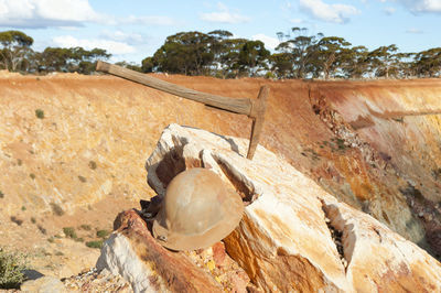 Close-up of axe on rock against sky