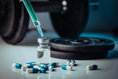 Dumbbells, syringe with needle, pills and vial with steroids. illegal doping in sport concept