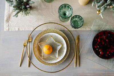 Stylish christmas dinner setting. gold and white plates, a star-shaped plate with tangerine