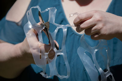 Midsection of woman cutting plastic with scissors