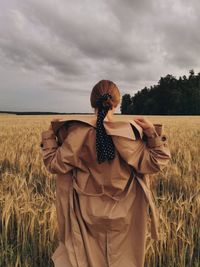 Rear view of woman standing on field against sky