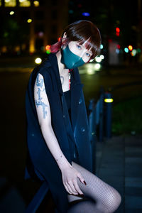 Young woman standing against illuminated city at night