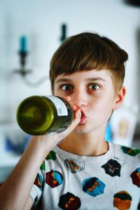 Portrait of a young boy drinking from a bottle of wine
