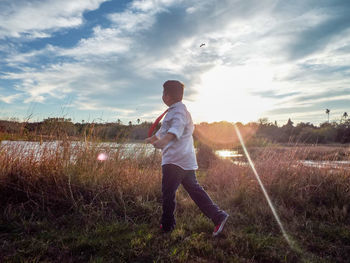 Low angle view of boy walking on field against sky