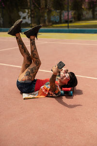 Caucasian girl with tattoos and short black hair on a sports court making a video call