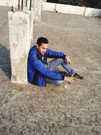 Full length of man sitting on sand at beach