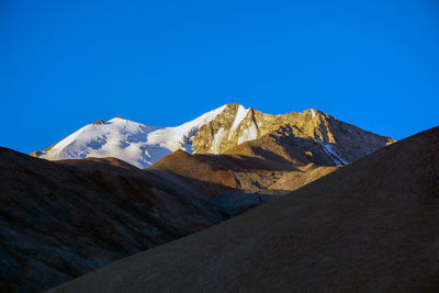 Scenic view of snowcapped mountains against clear blue sky