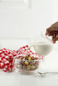 Pour fresh milk to a bowl of colorful fruitloops cereal. on white table
