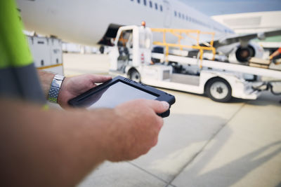 Ground staff preparing airplane before flight. worker using tablet against plane at airport.