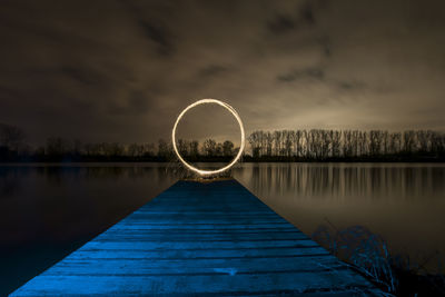 Wire wool on pier over lake against sky at night