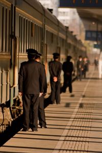 Rear view of train conductors standing by train on platform