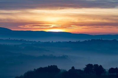 Scenic view of silhouette mountains against orange sky