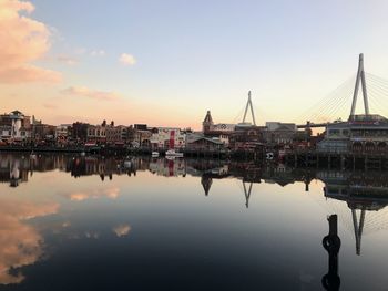 City by river against sky during sunset