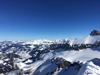 Scenic view of snowcapped mountains against clear blue sky