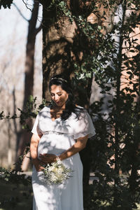 Portrait of woman standing against trees