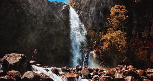 Men standing against waterfall