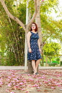 Portrait of young woman standing against tree