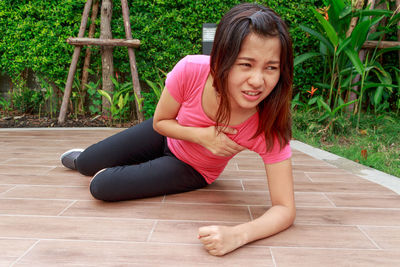 Young woman with chest pain lying on walkway