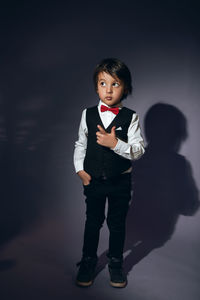 Stylish boy child of four years in the studio on the background in a vest and a red bow tie