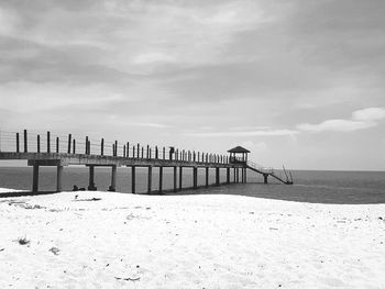 Wooden posts on beach against sky