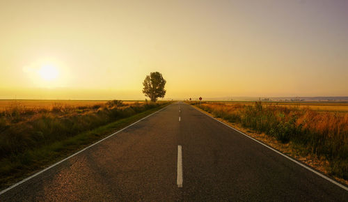 People walking on road against sky during sunset