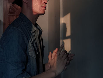 Midsection of man standing against wall at home