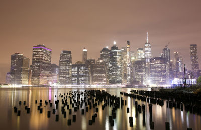 Illuminated modern buildings in city against sky at night