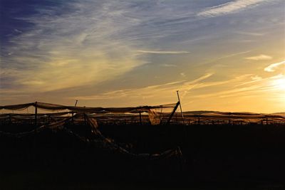 Silhouette cranes against sky during sunset