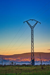 Electricity pylon on field against sky during sunset