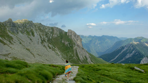 Man with umbrella on mountain against sky