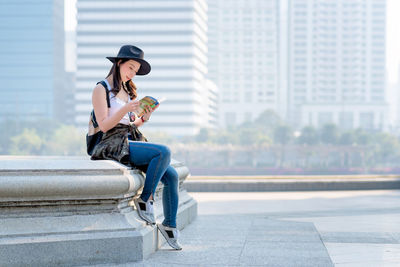 Young woman looking away while sitting in city